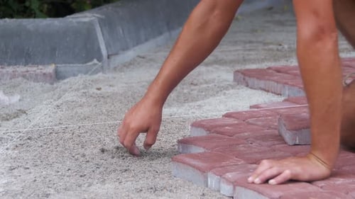 Construction Worker Lays Red Brick Sidewalk