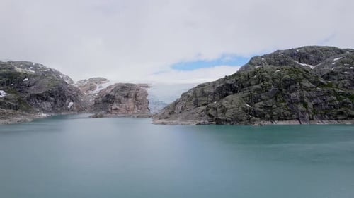 Drone Flight Towards Glacier Surrounded By Rocky Landscape And Fjord In Norway