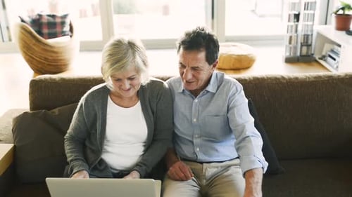 Senior Couple Relaxing On Sofa With Laptop