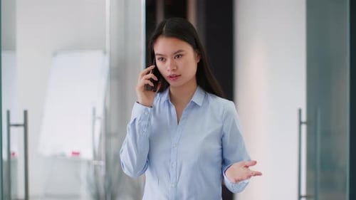 Businesswoman Engaged in a Phone Conversation in a Modern Office Setting