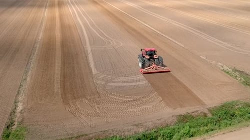Tractor at work, prepares the field for planting seeds. Aerial view.