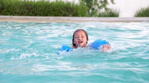 Happy hispanic latin blonde girl swimming in the pool in the outdoor pool