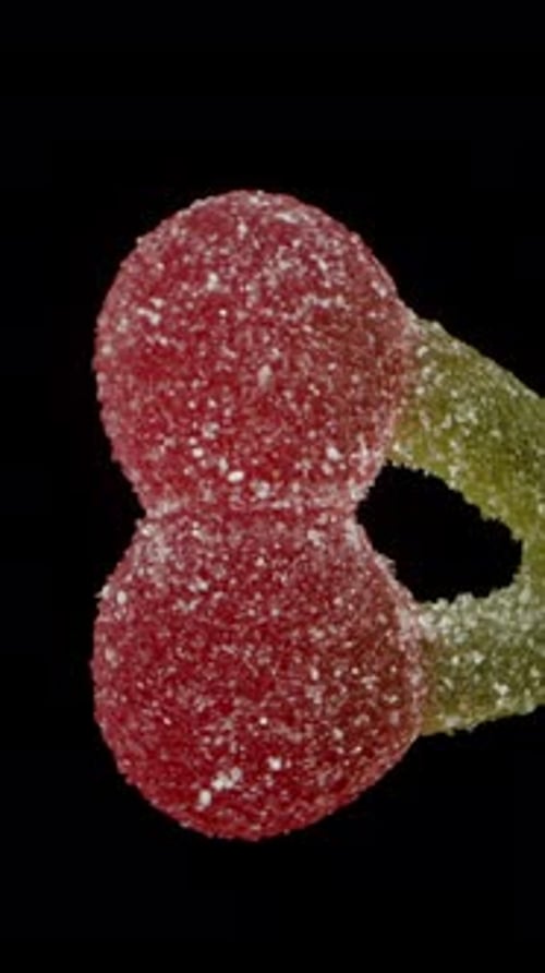 Vertical video. Gummy candy in the shape of a cherry branch with cherries in sugar, rotating