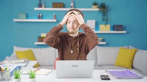 Frustrated angry young man looking at laptop with despair and anger.