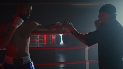 African American Boxer with Trainer Works on Punches and Blocks