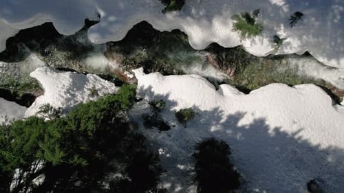 Drone Top View Flying Down Tree Branches To Snowy Spring Water