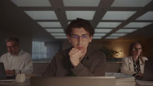 Jovem homem focado trabalhando no laptop durante a noite no escritório