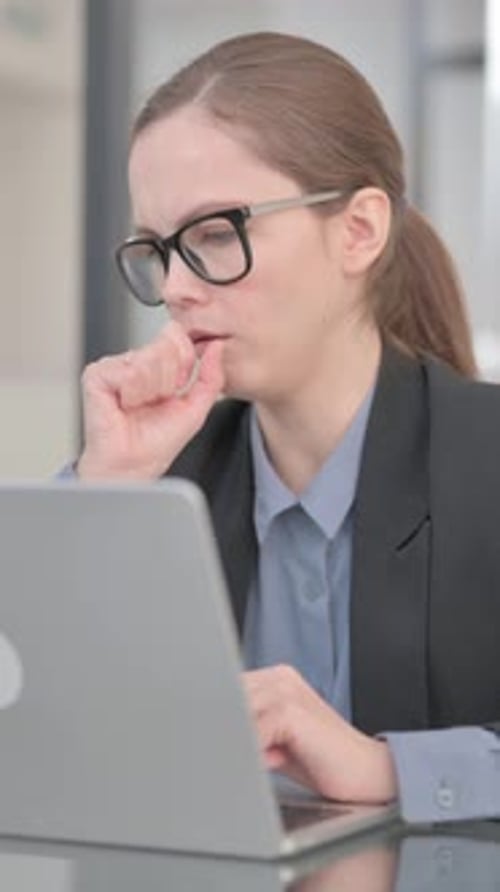 Woman Working at Laptop Coughing into Hand at Desk