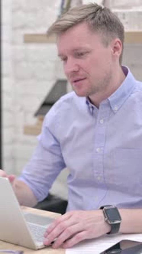 Man Video Calling on Laptop in Office Setting