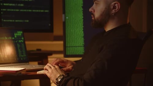 View of a Young Employee of an IT Company Working on a Laptop in the Office A Young Programmer Sits