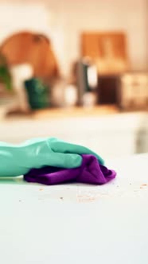 Gloved Hand Cleaning a White Surface