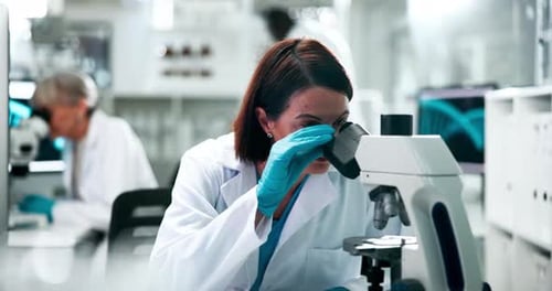 Focused Scientist Using Microscope in Modern Lab
