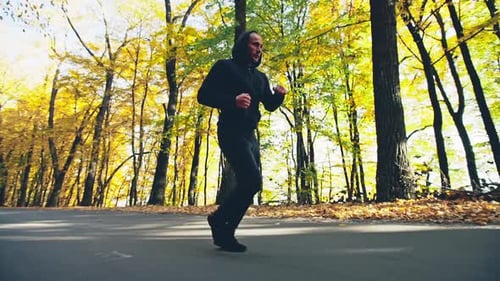 Lowangle Shot of a Determined Young Man Jogging on an Alley During Cardio Workout Outdoors in the