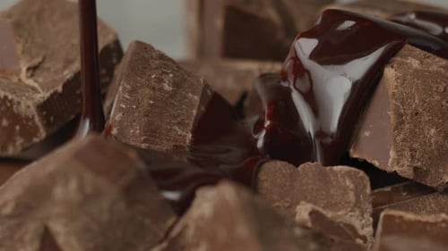 Melted Chocolate Pouring Over Chocolate Chunks in Studio
