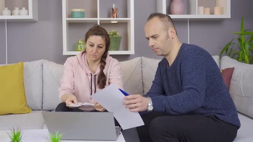La pareja que calcula sus facturas en papel en casa se encuentra en una situación difícil. Crisis económica.