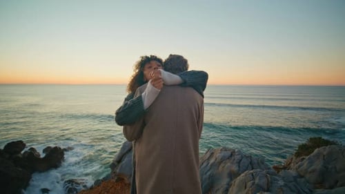 Couple Embrace on Rocky Coast at Sunrise