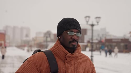 Traveler Observes City Man in Sweater Looks Across Individual in Orange Jacket Surveys Scene Person