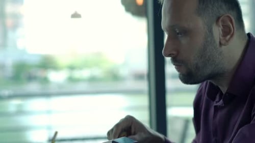 Young man enjoys a healthy lunch while working on his laptop in a bright cafe