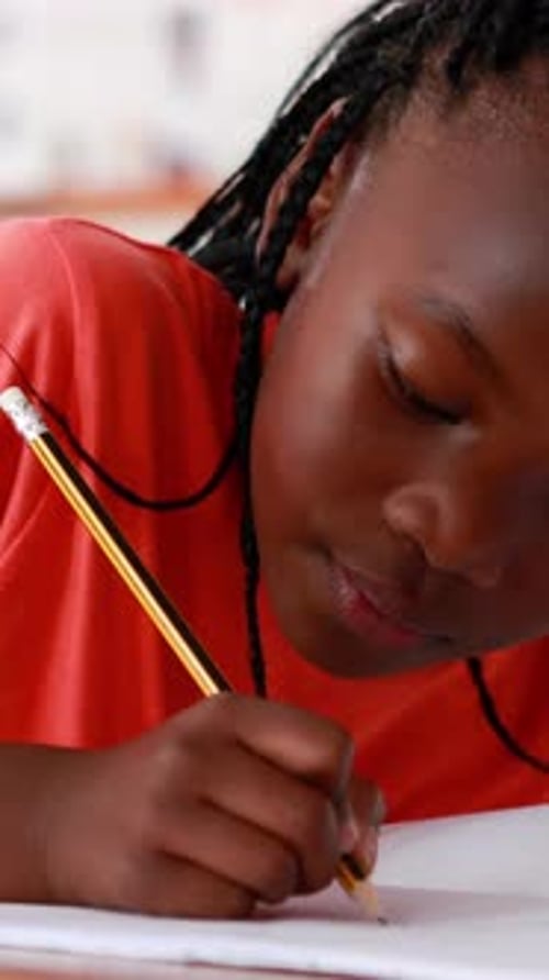 Vertical video of an African American girl focuses on her schoolwork at home