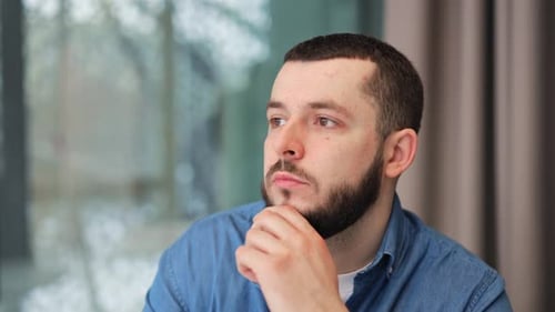 Thoughtful Man Contemplates by Window in Natural Light
