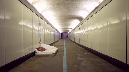 Homeless bed mattress in a bright tunnel in London at night, poverty problems in cities