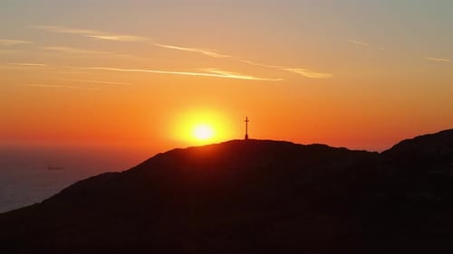 Sunset Over Hill with Prominent Cross and Ocean Horizon