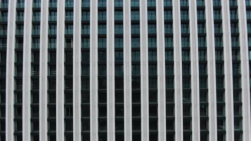 Construction Worker Ascending Scaffolding on a Modern Building Featuring a Sleek Glass Facade The