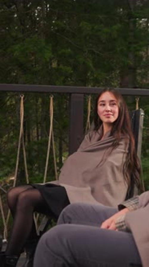 Woman Looks at Man Sitting in Armchair on Terrace