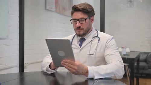 Middle Aged Doctor Using Digital Tablet in Clinic