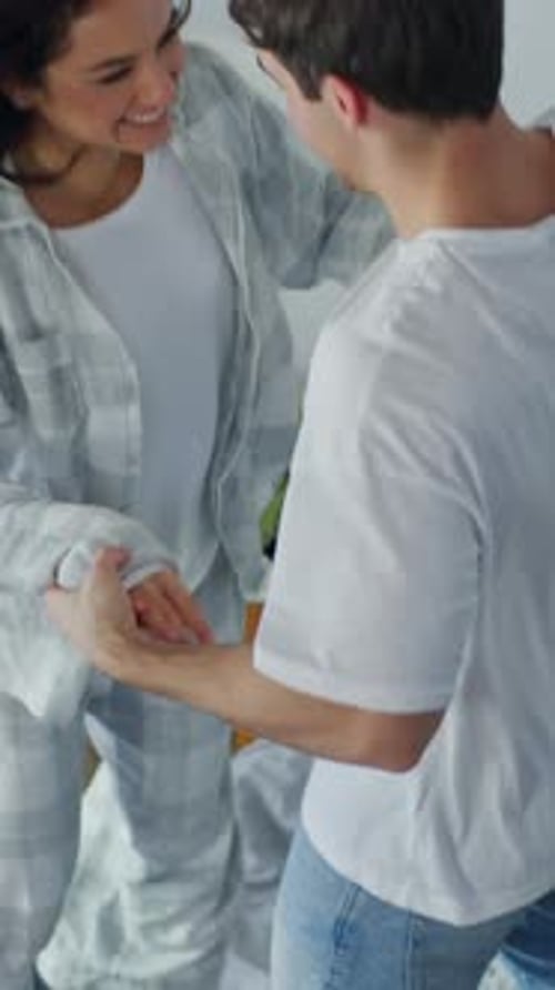 Playful Couple Holding Hands and Dancing Indoors