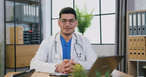 Smiling Doctor in Office With Laptop