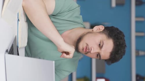 Young Man Works at Desk with Laptop and Notebook