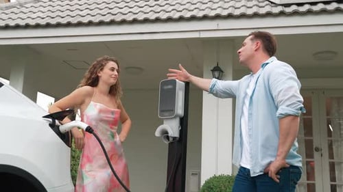 Happy couple recharge electric vehicle from EV charging station. Fastidious