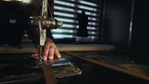 Tailor Sewing Leather on Antique Machine in Dark Room