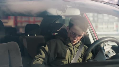 Young Adult Sits in Car During Daytime