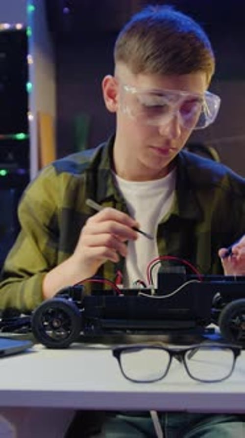 Teenager Building Toy Car Model at Table