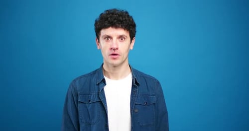 Surprised man expressing shock on blue background