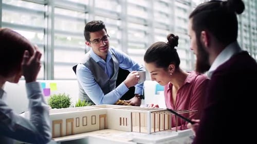 Group of Young Architects with Model of a House in Office, Talking