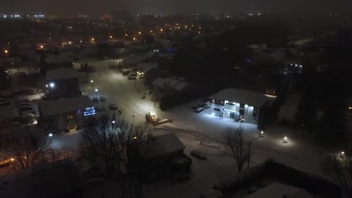Snowplow Clearing Suburban Streets at Night