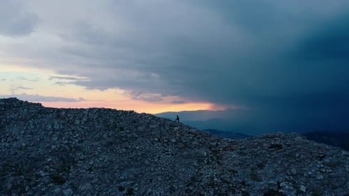 Tiny Silhouette of Man Walk on Mountain Ridge