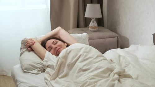 Woman Wakes Up and Stretches in Bed