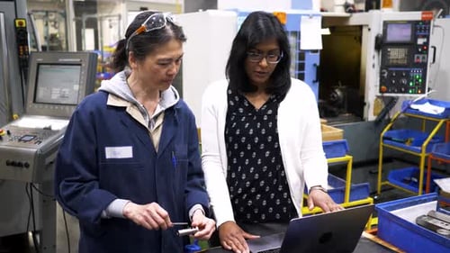 Female Manager and Worker Talking at Laptop in Manufacturing Plant 10 Seconds or Greater