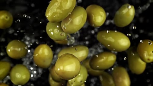 Green Olives Falling and Splashing with Water in Slow Motion