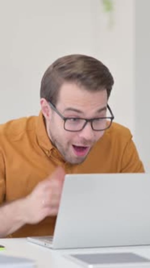 Excited Man Celebrating Success While Using Laptop Indoors