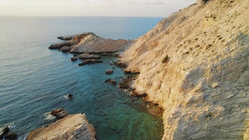 Steep rocky cliffside meets turquoise sea on Kefalonia rugged coastline in the morning light