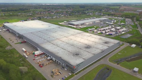 Aerial shot of industrial warehouse. Loading hub and many trucks with cargo trailers. Aerial view of