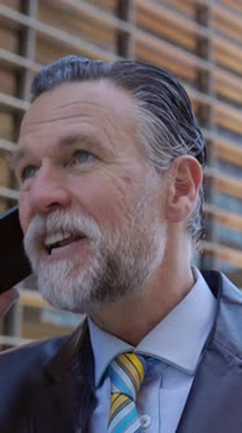 Professional Senior Manager Talking on Mobile Phone Over Office Buildings