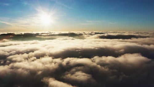 Soleil brillant au-dessus des nuages blancs duveteux au lever du soleil