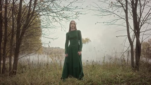 Model posing wearing green dress in a mysterious forest