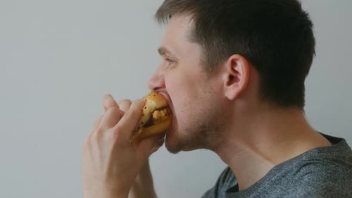Young Adult Man Enjoys Delicious Hamburger Indoors